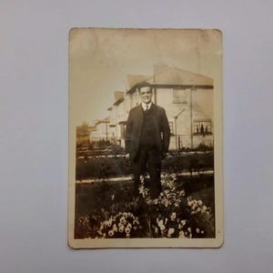 1930er Jahre Foto des Mannes Vintage Schwarzweißfoto aus Irland des jungen Mannes im Anzug mit Gartenlandschaft und Häuserzeile im Hintergrund