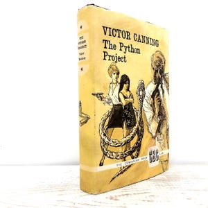 Puede incluir: Un libro de tapa dura titulado The Python Project de Victor Canning con una sobrecubierta amarilla. La portada presenta una ilustración en tinta negra de dos figuras, una serpiente grande y una pistola. El lomo muestra el título y el autor.