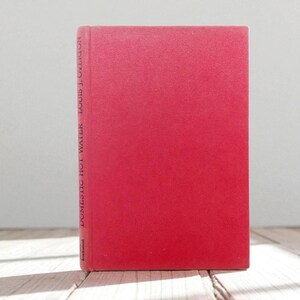 May include: A vintage book with a red cover. The book's spine displays the title "DOMESTIC HOT WATER" and the author's name, "LOUIS J. OVERTON." The publisher's name, "Lockwood," is also visible. The book is standing upright.