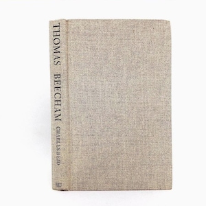 May include: A hardcover book with a beige linen cover. The spine features the title "THOMAS BEECHAM" in vertical black text, with "CHARLES REID" below. The book has a simple, classic design, suitable for a library or home decor.