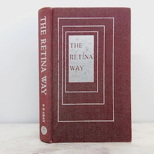 Puede incluir: Un libro de tapa dura granate titulado "THE RETINA WAY" con letras blancas. La portada presenta un diseño rectangular con el título en un rectángulo plateado. El nombre del autor está en el lomo.