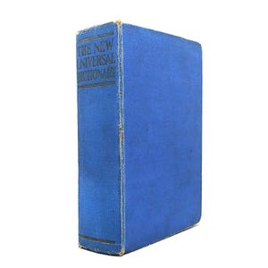 May include: A vintage blue hardcover book titled "THE NEW UNIVERSAL DICTIONARY" in gold lettering. The book has a worn appearance, with visible wear and tear along the spine and edges, suggesting age and use. The background is plain white.