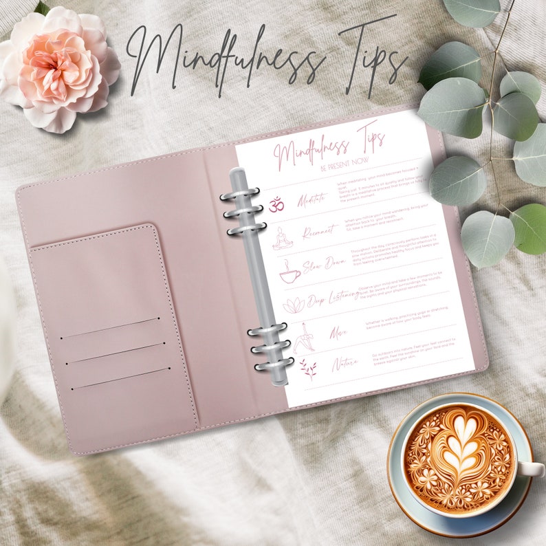May include: A pink leather bound journal with a white page open to a list of mindfulness tips. The tips include meditation, movement, slow down, deep listening, move, and nature. The journal is on a white fabric surface with a cup of coffee with latte art.