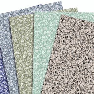 Könnte beinhalten: Eine Sammlung von Papierbögen mit Mustern in verschiedenen Farben, darunter Blau, Grün und Beige. Jedes Blatt zeigt ein sich wiederholendes Blumenmuster in Weiß oder Schwarz, wodurch ein vielseitiges Set für Bastelarbeiten und Schreibwaren entsteht.