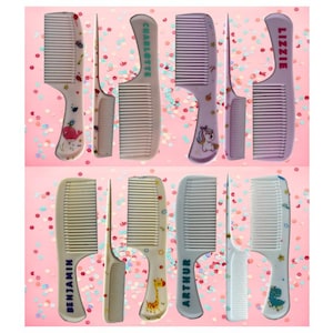 May include: A selection of personalised combs in shades of pink, purple, and beige. Each comb is inscribed with a name, such as "LIZZIE" or "BENJAMIN", and decorated with animal motifs. The set includes combs of different sizes.
