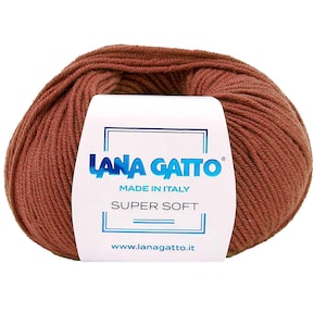 Könnte beinhalten: Ein Knäuel terrakottafarbenes Garn, umwickelt mit einem weißen Papieretikett. Das Etikett zeigt den blauen Schriftzug LANA GATTO, die Worte MADE IN ITALY, den Text SUPER SOFT sowie die Website-Adresse www.lanagatto.it in blauer Schrift.