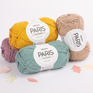 May include: Four balls of Drops Paris yarn in different colors: yellow, green, beige, and purple. The yarn is 100% cotton and is labeled 'Drops Paris Uni Colour'.