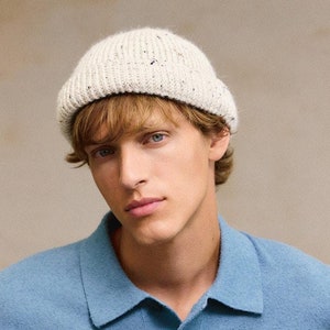 Peut inclure: Un homme portant une chemise à manches longues bleu clair avec un bonnet en tricot blanc. La chemise a un col boutonné et trois boutons.