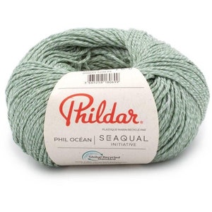 May include: A ball of light green yarn with a white paper label featuring the red Phildar logo, the text Phil Ocean, Seaqual Initiative, and a barcode. The yarn has a textured, multi-tonal appearance with subtle white flecks throughout the fibers.