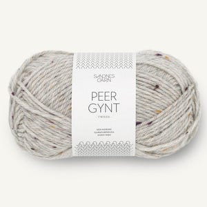 May include: A ball of light gray yarn with flecks of brown, white, and purple. The yarn is labeled 'Sandnes Garn Peer Gynt - Tweed - Den Norske Garnfabrikken Siden 1889.'