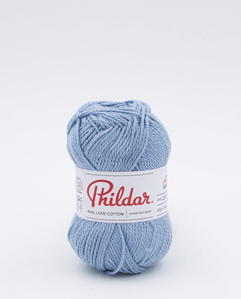 Puede incluir: Un ovillo de hilo de algod&oacute;n Phil Love Cotton de color azul claro de la marca Phildar. La etiqueta dice "Phil Love Cotton" y "Coton Tout Doux".