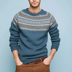 May include: A blue sweater with a brown and white geometric pattern around the neck. The sweater has long sleeves and a crew neck.