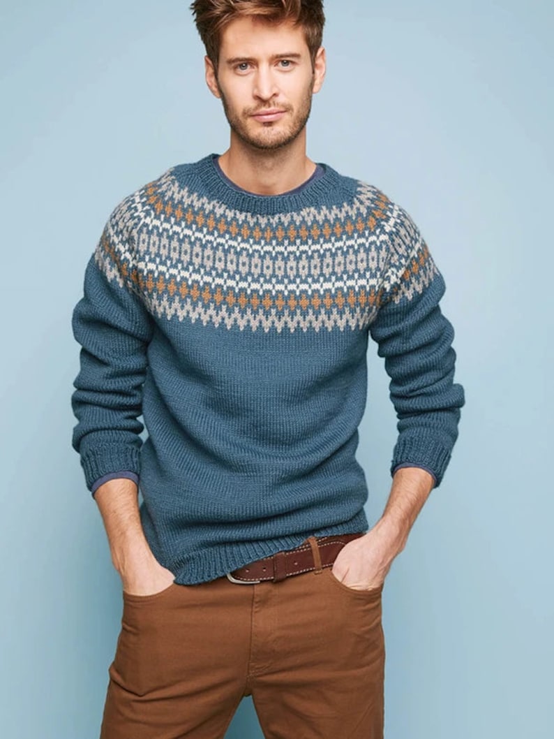May include: A blue sweater with a brown and white geometric pattern around the neck. The sweater has long sleeves and a crew neck.