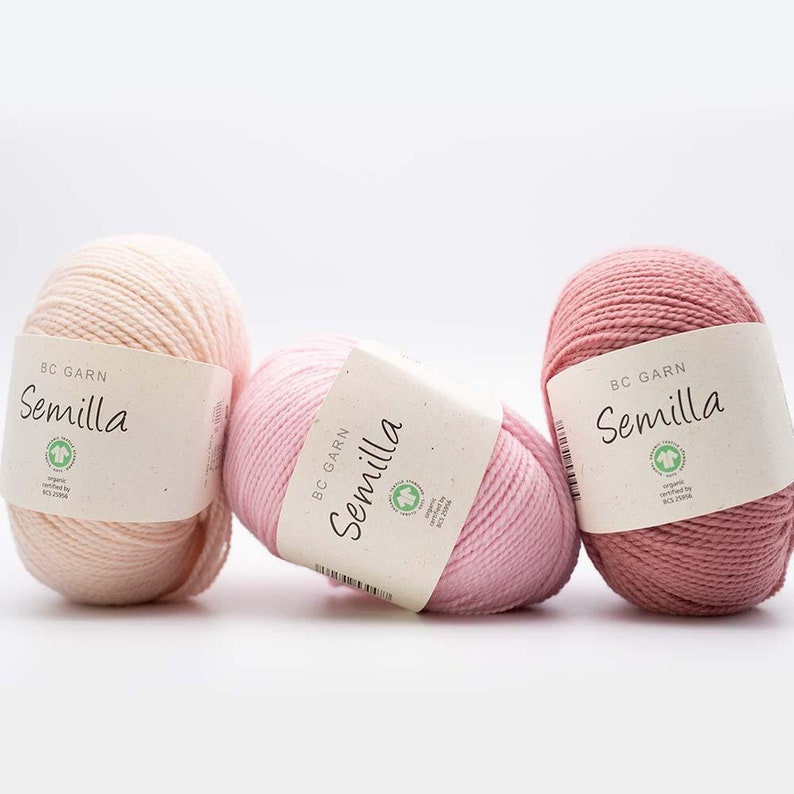 May include: Three balls of yarn in different shades of pink. The yarn is labelled "Semilla BC Garn" and is certified organic.