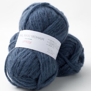 May include: Two balls of navy blue yarn with a white label wrapped around one. The label reads "PHIL MAXI MOHAIR" and lists the fiber content. The yarn is a soft, fluffy texture, perfect for knitting or crocheting projects.