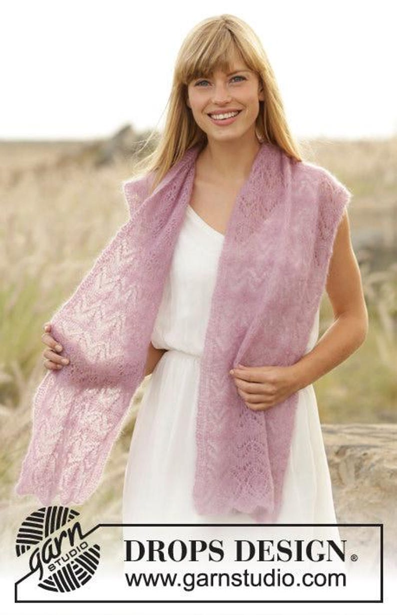 May include: A light purple, open-weave scarf draped over a white dress. The scarf has a delicate, lacy pattern. The image includes the text "DROPS DESIGN" and the website address www.garnstudio.com.