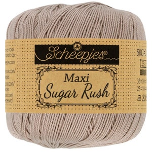 Puede incluir: Un ovillo de hilo beige etiquetado como "Scheepjes Maxi Sugar Rush" con un peso de 50g.