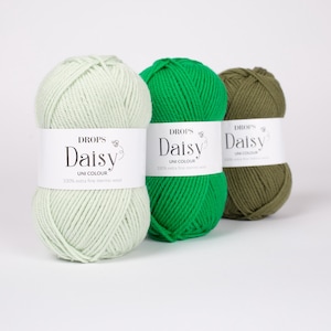 May include: Three skeins of Drops Daisy yarn arranged in a row. The first is light mint green, the second is vibrant grass green, and the third is olive green. Each skein features a white paper label with the text Drops Daisy Uni Colour.