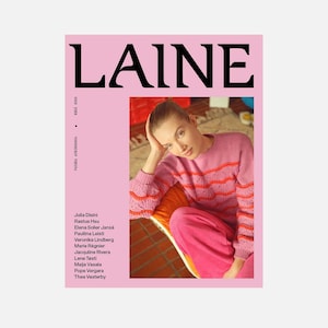 May include: A pink magazine cover with the word "LAINE" in large black letters. The cover features a woman wearing a pink sweater with orange stripes and pink corduroy pants. The text "PAIKKA AURINGOSSA" and "KESA 2013" are also visible.
