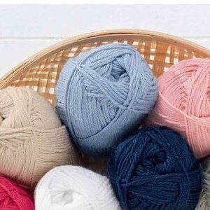 Puede incluir: Una cesta de hilo de diferentes colores, incluyendo azul claro, rosa, beige, blanco, azul marino y gris.