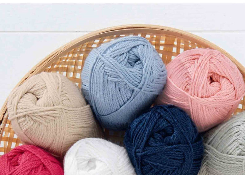 Puede incluir: Una cesta de hilo de diferentes colores, incluyendo azul claro, rosa, beige, blanco, azul marino y gris.