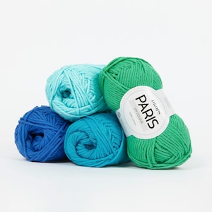 K&ouml;nnte beinhalten: Eine Ansammlung von Garnkn&auml;ueln in verschiedenen Blau- und Gr&uuml;nt&ouml;nen. Ein Kn&auml;uel tr&auml;gt ein Etikett mit der Aufschrift "DROPS PARIS UNI COLOUR 100% Cotton". Die Kn&auml;uel sind vor einem wei&szlig;en Hintergrund gestapelt.