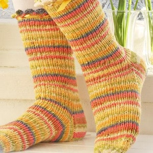 May include: A pair of mid-calf knit socks featuring a multi-colored striped pattern in shades of yellow, orange, pink, and blue. The socks have a scalloped crocheted top edge accented with a thin yellow ribbon tied in a small bow at the front.