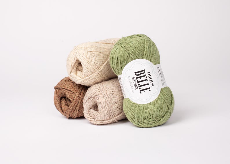 May include: A collection of yarn skeins in various colors, including brown, beige, and green. One skein has a label that reads "DROPS BELLE uni colour". The yarn is arranged on a white background.