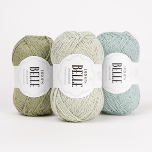 May include: Three skeins of Drops Belle yarn in shades of green and blue. Each skein has a white label with the text "BELLE" and "Unicolour Everyday luxury!" The yarn is arranged against a white background.