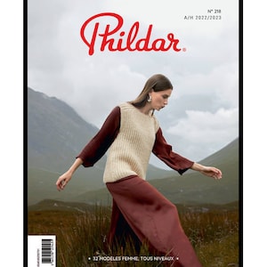 Puede incluir: Una portada de revista con una mujer que lleva un chaleco de punto crema y una falda color burdeos. La revista se titula "Phildar" y tiene el número 218 y el texto "A/H 2022/2023". El texto "32 MODÈLES FEMME, TOUS NIVEAUX" también es visible en la portada.