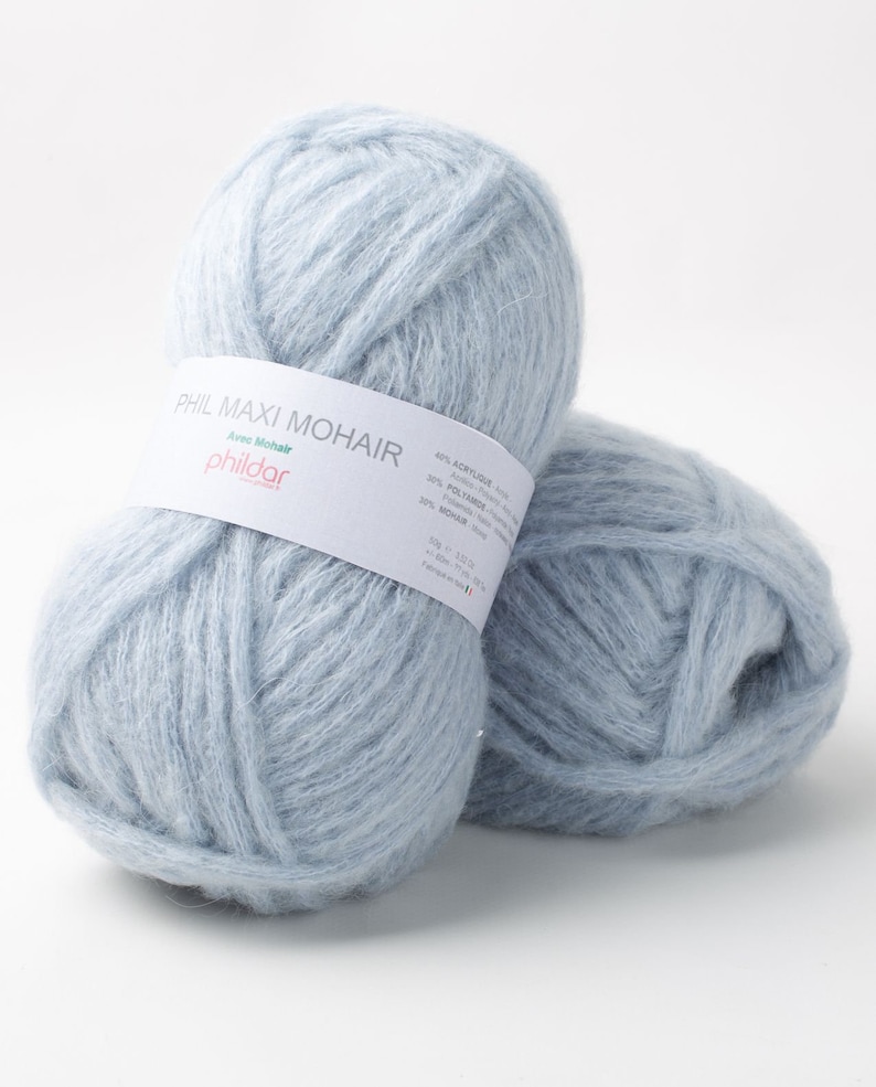 May include: Two light blue yarn balls with a soft, fluffy texture. The yarn is labeled "PHIL MAXI MOHAIR" with the brand name "phildar" visible. The label also lists the yarn's composition: 40% Acrylic, 30% Polyamide, and 30% Mohair.