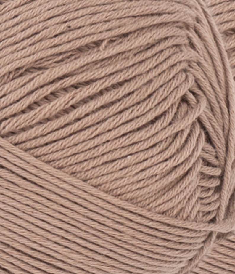 May include: Close-up of a ball of tan yarn. The yarn is tightly wound, with visible individual strands creating a textured surface. The color is a warm, neutral tone, suitable for various knitting or crochet projects.