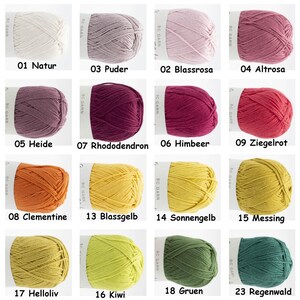 Puede incluir: Una colecci&oacute;n de 12 ovillos de lana en varios colores, incluyendo natural, rosa, rojo, naranja, amarillo y verde. Cada ovillo est&aacute; etiquetado con un n&uacute;mero y una palabra alemana que describe el color.