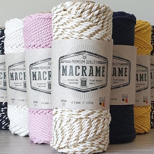 Puede incluir: Surtido de cordón de algodón de 10 mm en varios colores, incluyendo negro, blanco, rosa, dorado y amarillo. Cada carrete tiene una etiqueta con el texto "Macramé" y "Calidad Premium".