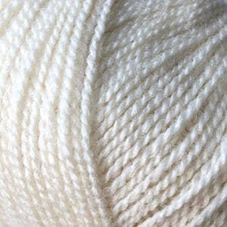 May include: Close-up of a ball of off-white yarn. The yarn is tightly wound, showing individual strands with a slightly textured appearance. The color is a soft, creamy white, ideal for knitting or crocheting projects.