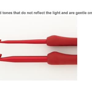Puede incluir: Dos agujas de crochet rojas con mangos ergon&oacute;micos. Las agujas est&aacute;n hechas de pl&aacute;stico rojo mate, suave para los ojos.