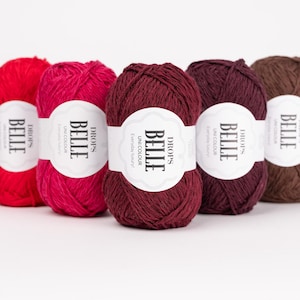 May include: Five skeins of Drops Belle yarn in various colors: red, fuchsia, burgundy, dark purple, and brown. Each skein has a white label with the text "BELLE" and "UNI COLOUR". The yarn is for knitting and crochet projects.