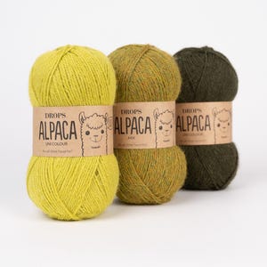May include: Three skeins of yarn arranged in a row, featuring a bright lime green, a mottled olive green, and a dark forest green. Each skein is wrapped in a tan paper band labeled DROPS ALPACA with a line drawing of an alpaca face.