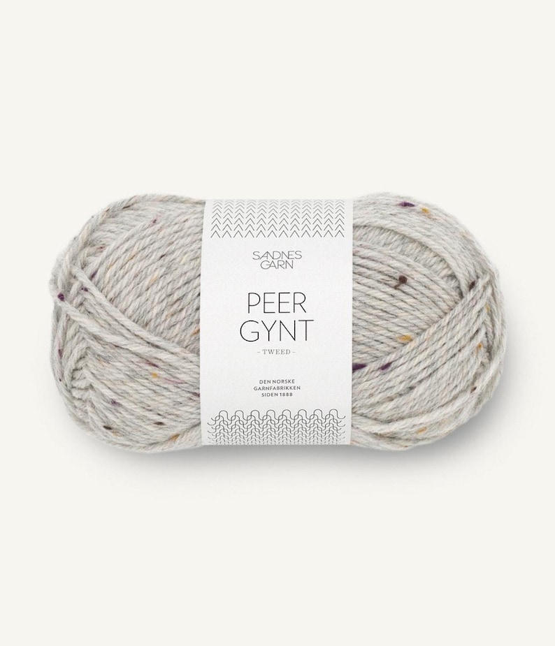 May include: A ball of light gray yarn with flecks of brown, white, and purple. The yarn is labeled 'Sandnes Garn Peer Gynt - Tweed - Den Norske Garnfabrikken Siden 1889.'