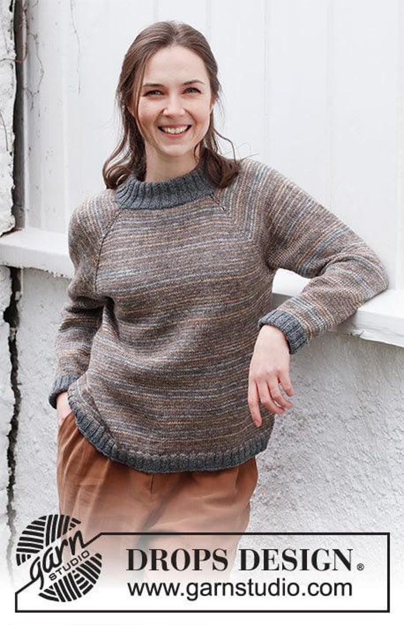 May include: A long-sleeved knit sweater featuring a heathered brown, gray, and orange horizontal striped pattern. The garment has a solid dark gray ribbed crew neckline, matching ribbed cuffs, and a ribbed hemline with raglan sleeve detailing.
