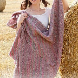 May include: A large, rectangular knitted shawl featuring a variegated color palette of soft pink, muted red, and earthy brown tones. The fabric displays a fine, consistent knit texture with vertical color transitions throughout the entire piece.