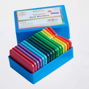 May include: A blue plastic box containing a rainbow assortment of Knit Pro Rainbow Knit Blockers. The box lid features the Knit Pro logo and the text "Rainbow Knit Blockers for efficient and effective blocking of your projects".