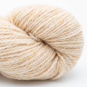 May include: A skein of cream-colored yarn with a subtle fleck of yellow.
