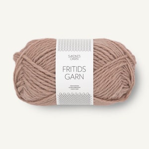 May include: A skein of dusty rose colored yarn wrapped in a white paper label. The label features the text SANDNES GARN, FRITIDS GARN, and DEN NORSKE GARNFABRIKKEN SIDEN 1888, along with black chevron and wave patterns at the top and bottom edges.