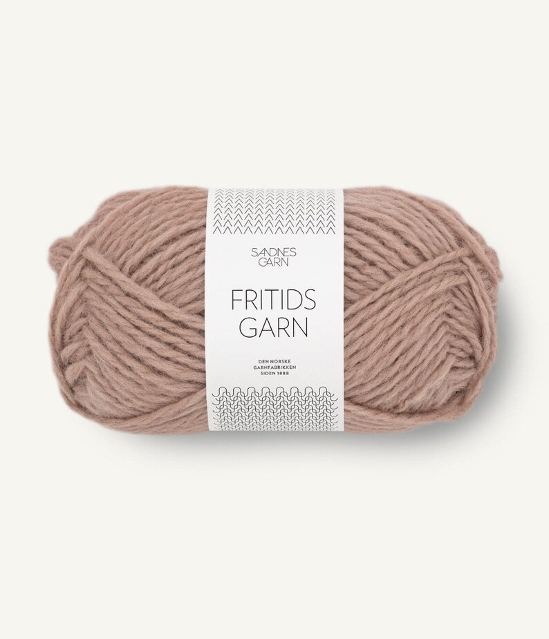 May include: A skein of dusty rose colored yarn wrapped in a white paper label. The label features the text SANDNES GARN, FRITIDS GARN, and DEN NORSKE GARNFABRIKKEN SIDEN 1888, along with black chevron and wave patterns at the top and bottom edges.