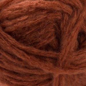 May include: Close-up of a ball of brown yarn. The yarn has a fluffy, textured appearance, with visible strands and a rich, earthy color. The fibers are tightly wound, creating a dense, soft ball, suitable for knitting or crocheting projects.