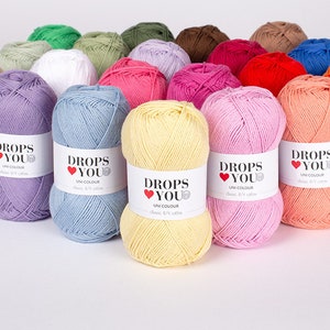 Puede incluir: Una colecci&oacute;n de ovillos de lana coloridos en varios tonos, incluyendo lavanda, azul, rosa y naranja. Cada ovillo tiene una etiqueta blanca con el texto "DROPS YOU" y "UNI COLOUR". La lana est&aacute; dispuesta de forma visualmente atractiva.