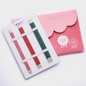 May include: A set of KnitPro interchangeable knitting needles in a white case with a pink carrying pouch. The needles are in three colors: red, pink, and green. The pouch has a white sheep design.