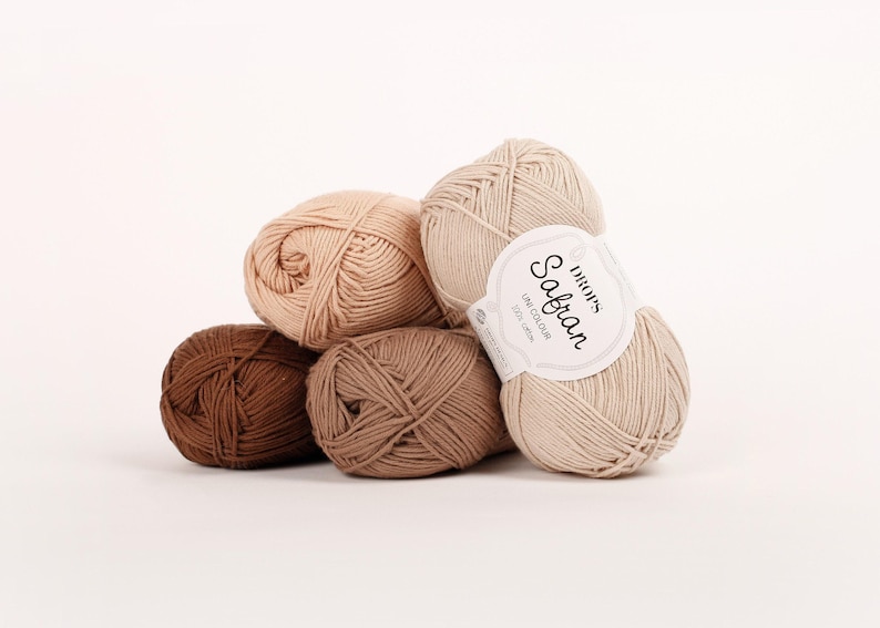 May include: Four balls of yarn in various shades of brown. The yarn is labeled 'DROPS Sabran, One Colour, 50g, 100m.'