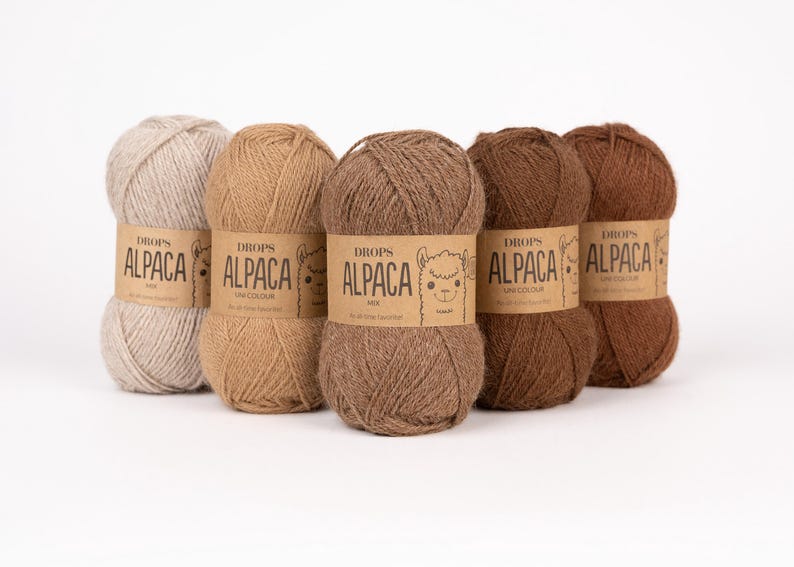 May include: Five skeins of Drops Alpaca yarn arranged in a row, featuring a gradient of neutral earth tones from light beige to dark brown. Each ball of yarn is wrapped in a tan paper label with the text Drops Alpaca and a small alpaca illustration.